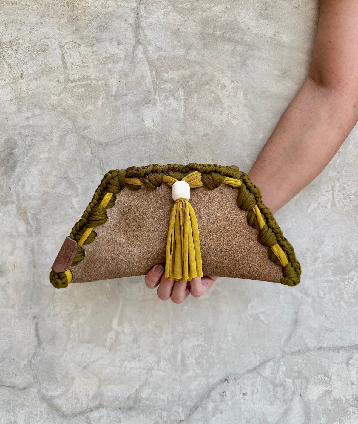 Kora clutch photographed against a natural grey wall, full view