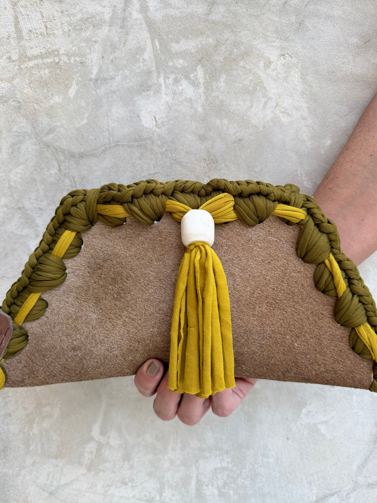 Close-up detail of Kora clutch against a natural grey wall