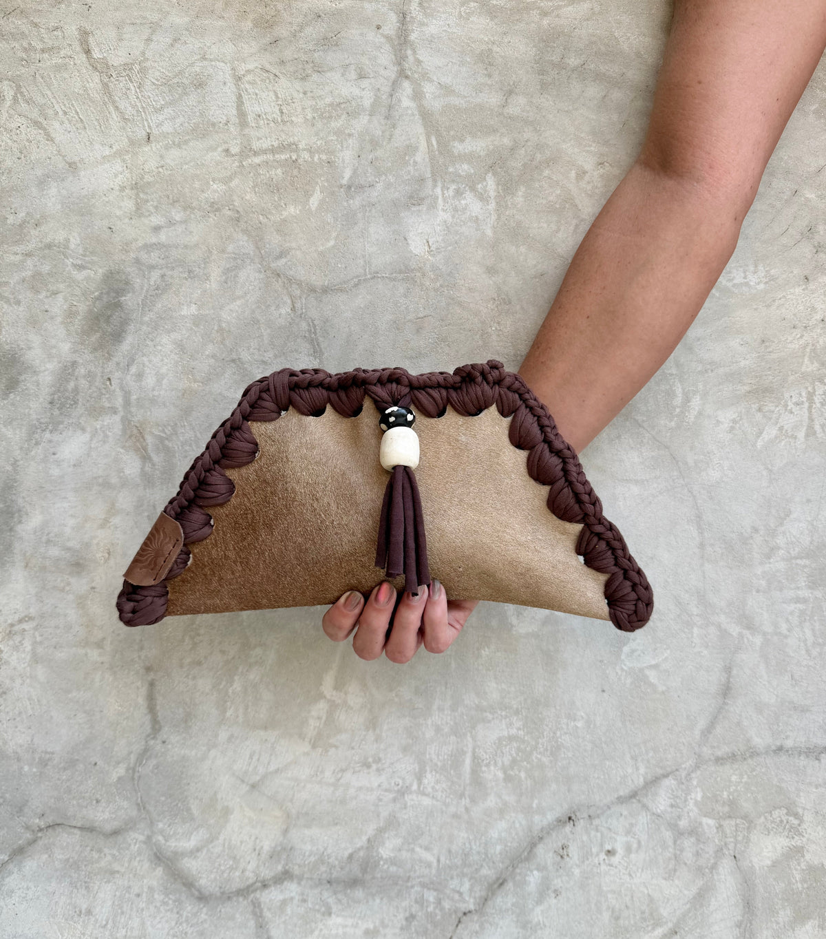 Kora clutch photographed against a natural grey wall, full view
