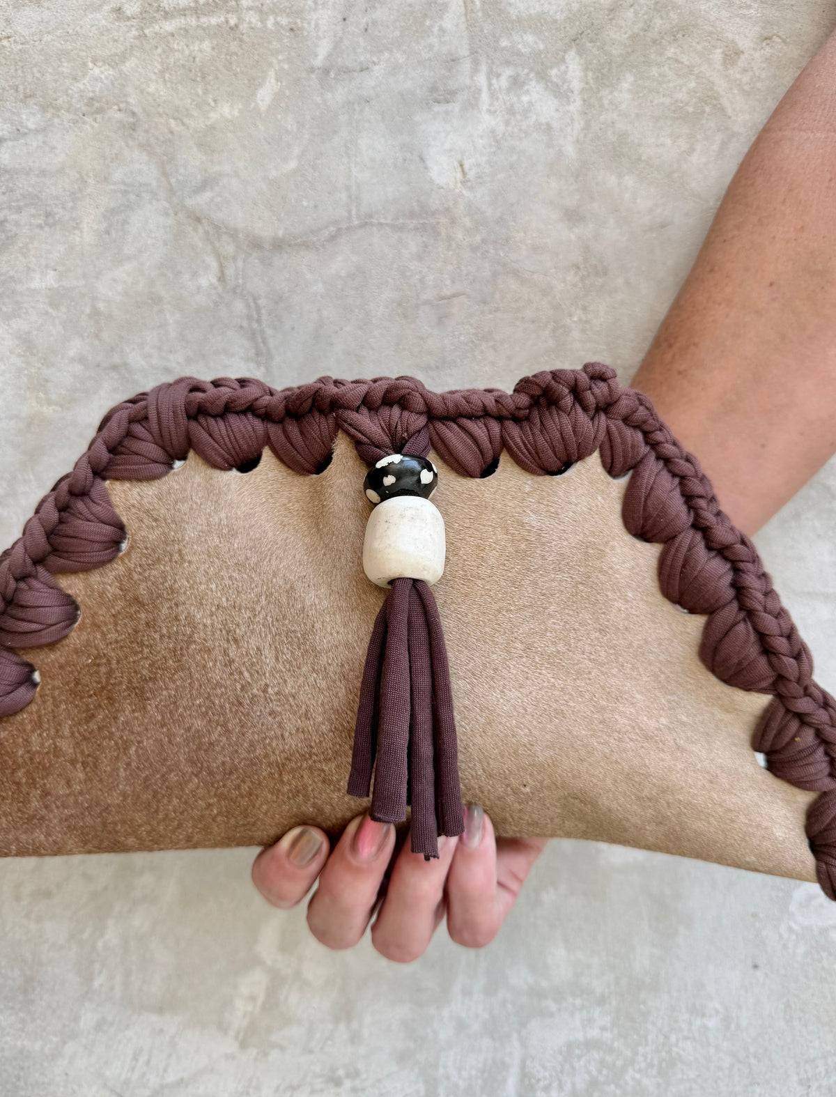 Close-up detail of Kora clutch against a natural grey wall