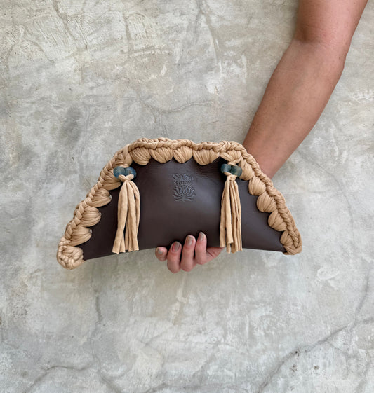 Kora clutch photographed against a natural grey wall, full view