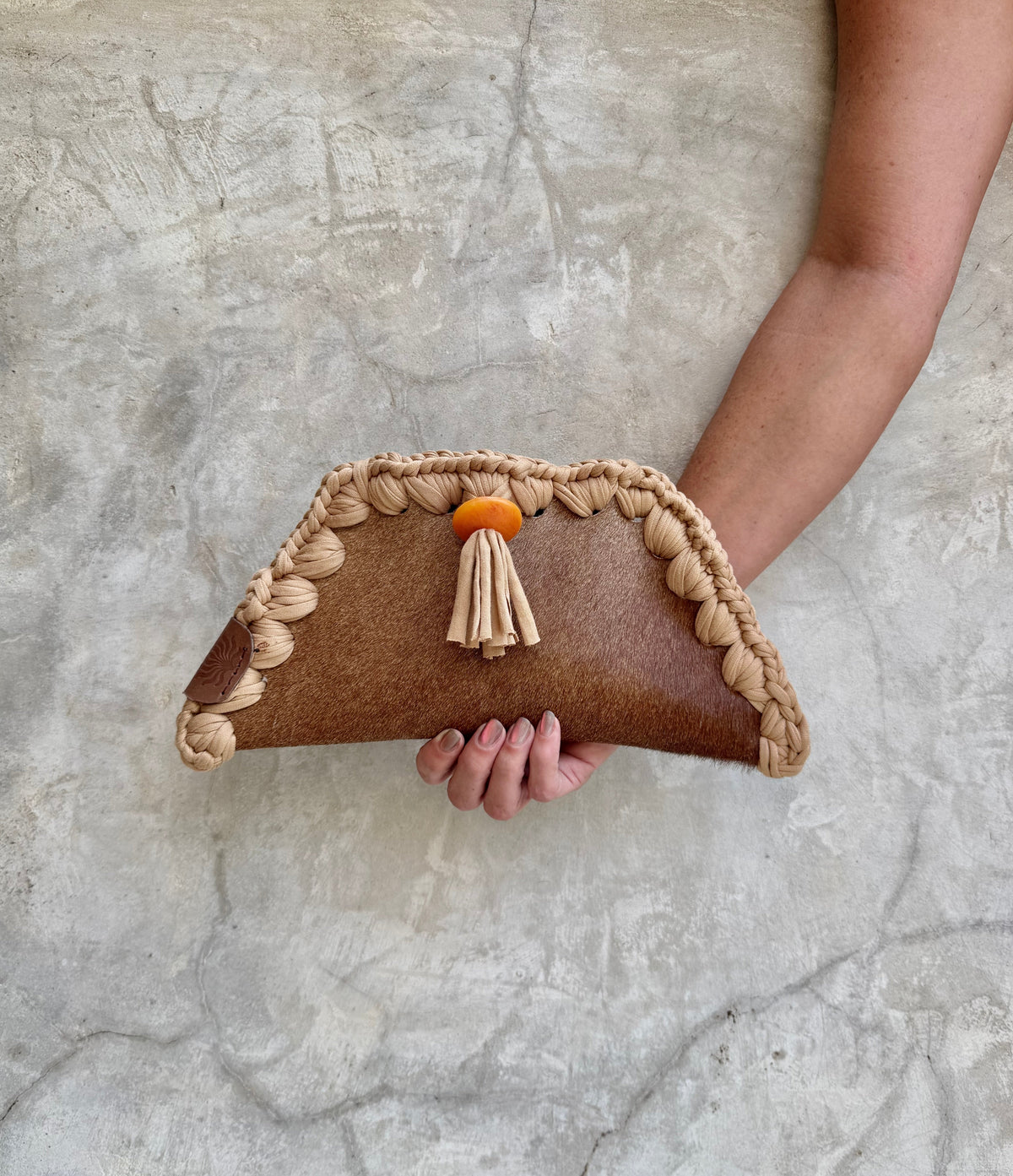 Kora clutch photographed against a natural grey wall, full view