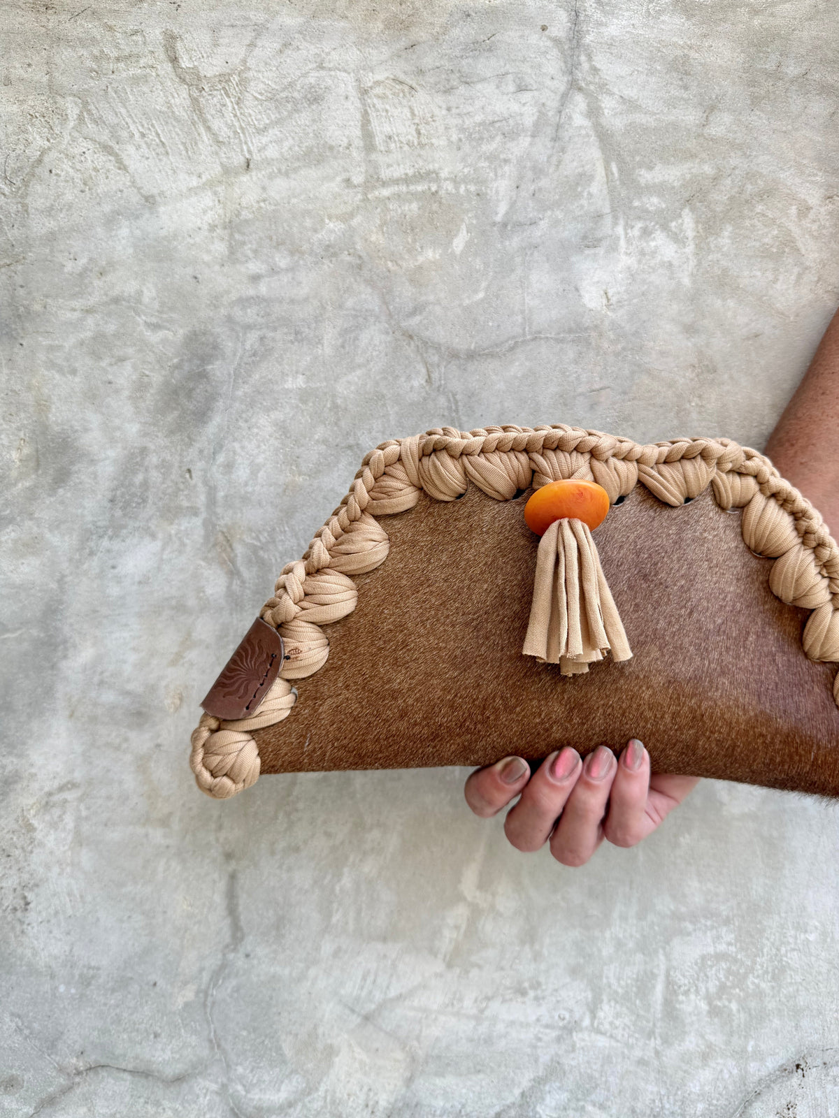 Close-up detail of Kora clutch against a natural grey wall
