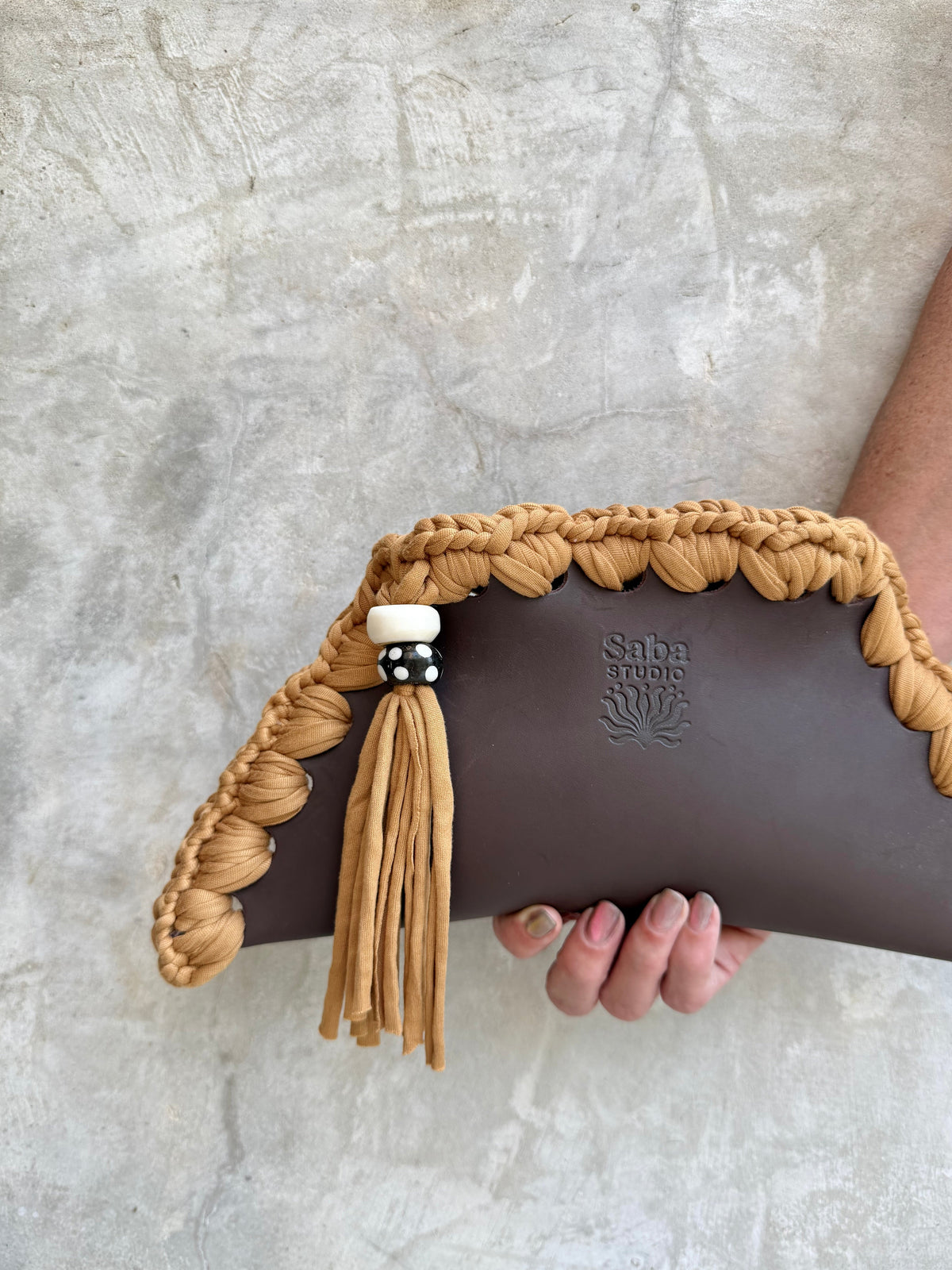 Close-up detail of Kora clutch against a natural grey wall
