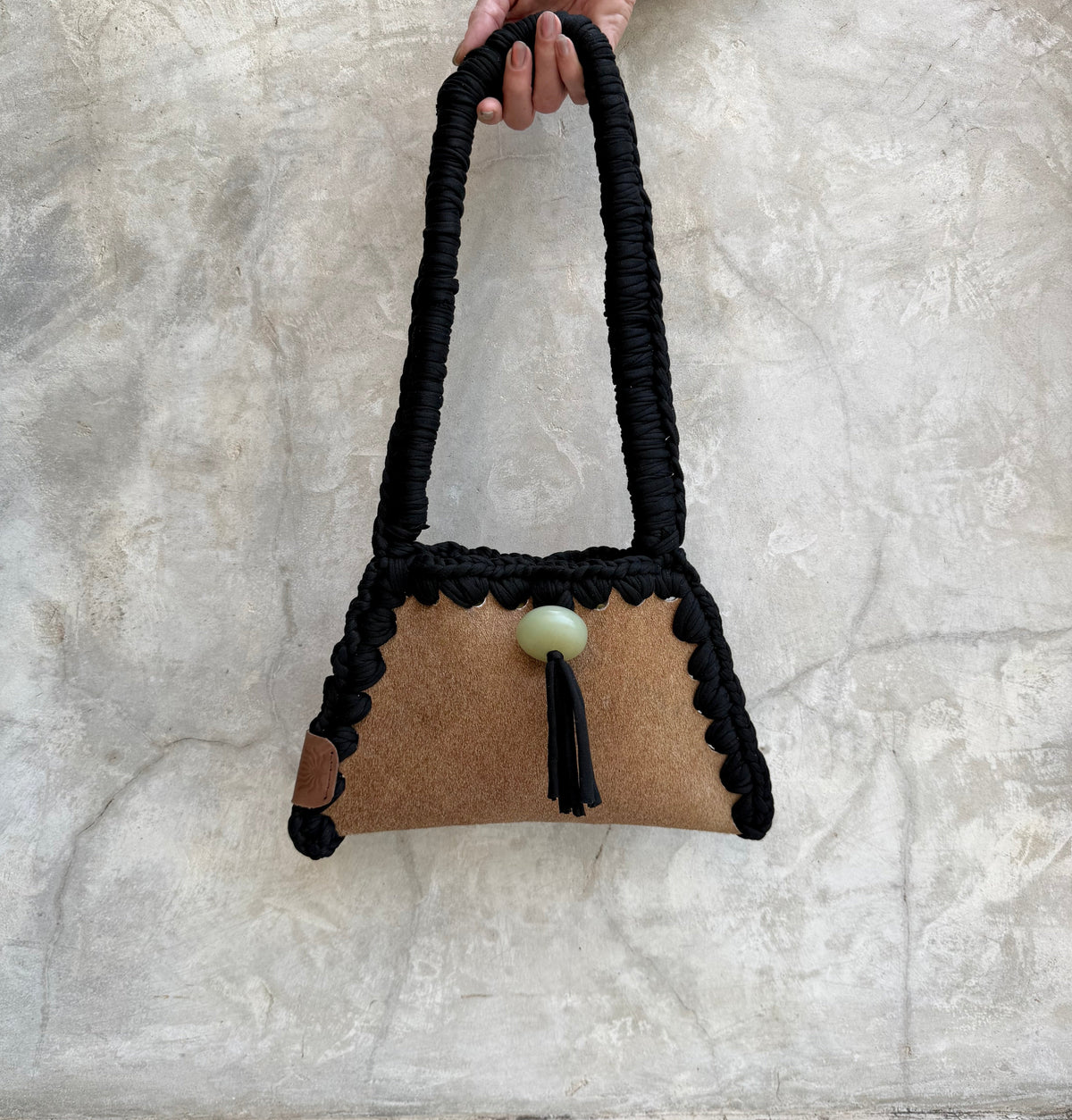 Solara shoulder bag photographed against a natural grey wall, full view