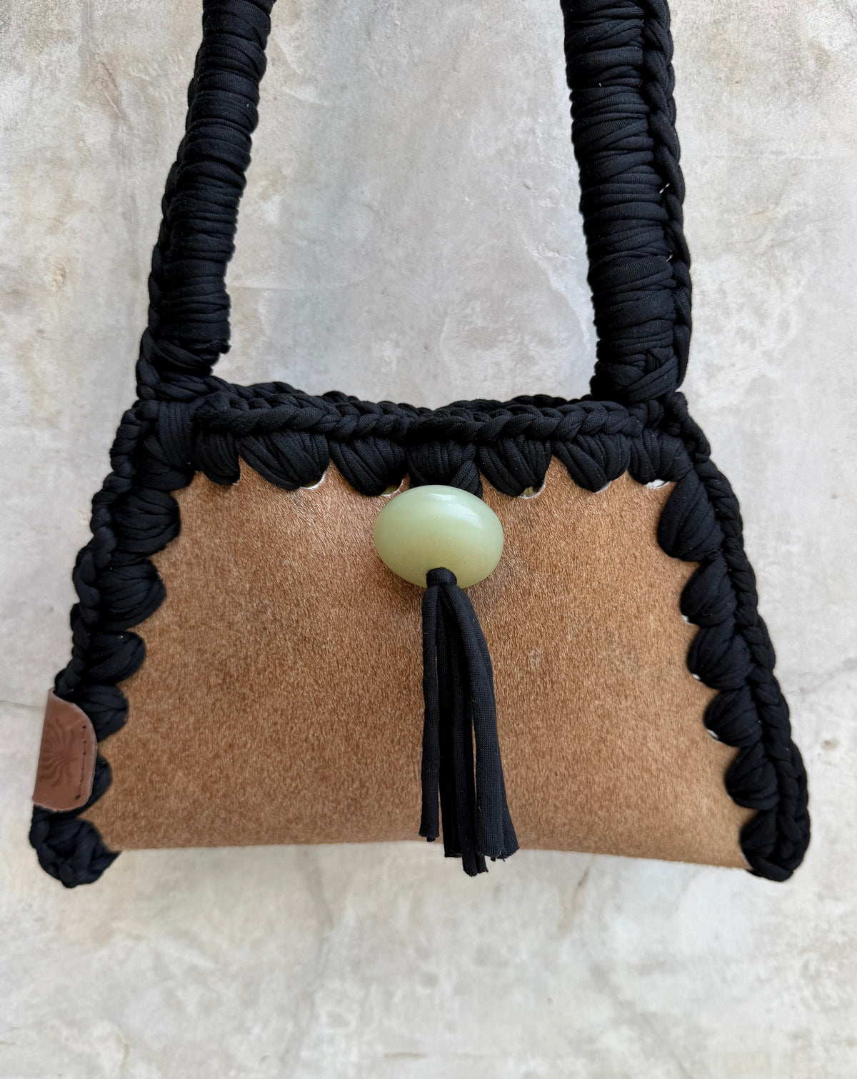 Close-up detail of Solara shoulder bag against a natural grey wall