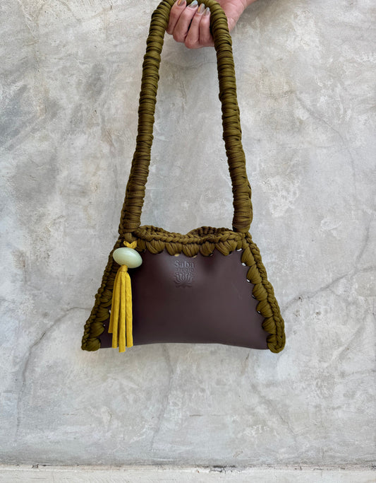 Solara shoulder bag photographed against a natural grey wall, full view