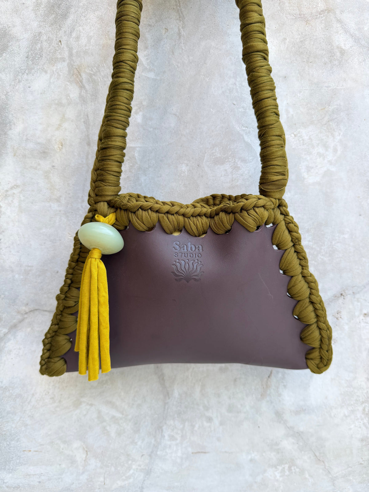 Close-up detail of Solara shoulder bag against a natural grey wall
