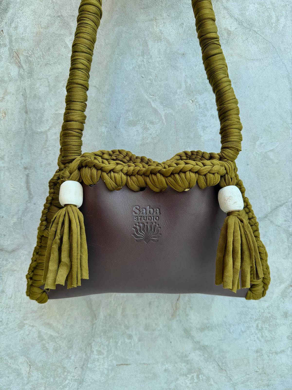 Close-up detail of Solara shoulder bag against a natural grey wall