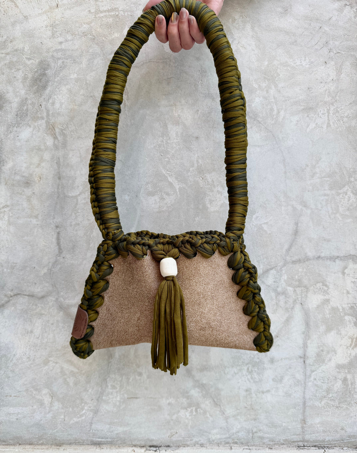 Solara shoulder bag photographed against a natural grey wall, full view