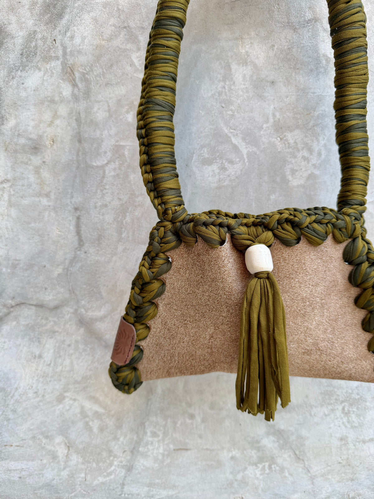 Close-up detail of Solara shoulder bag against a natural grey wall