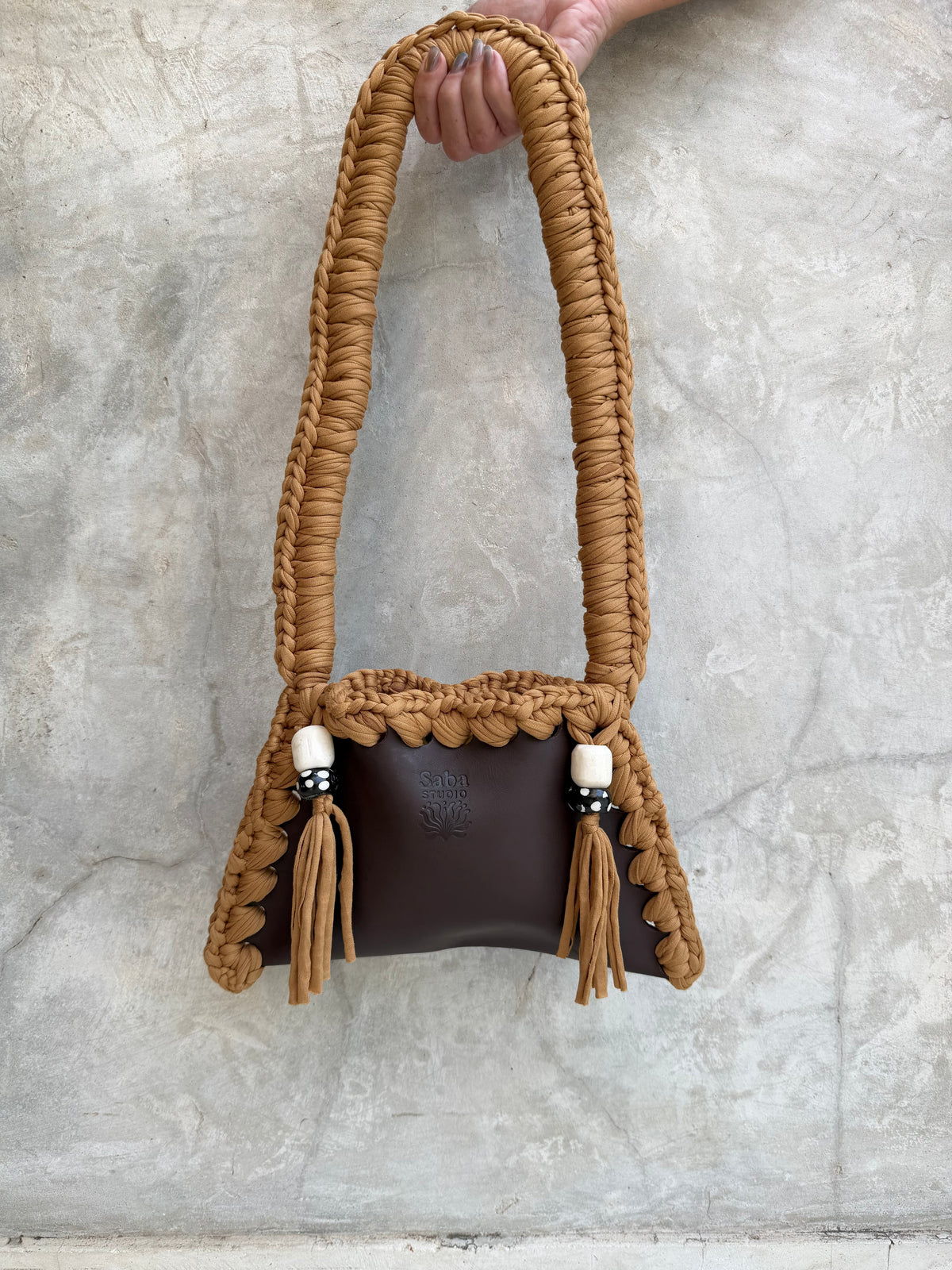 Solara shoulder bag photographed against a natural grey wall, full view