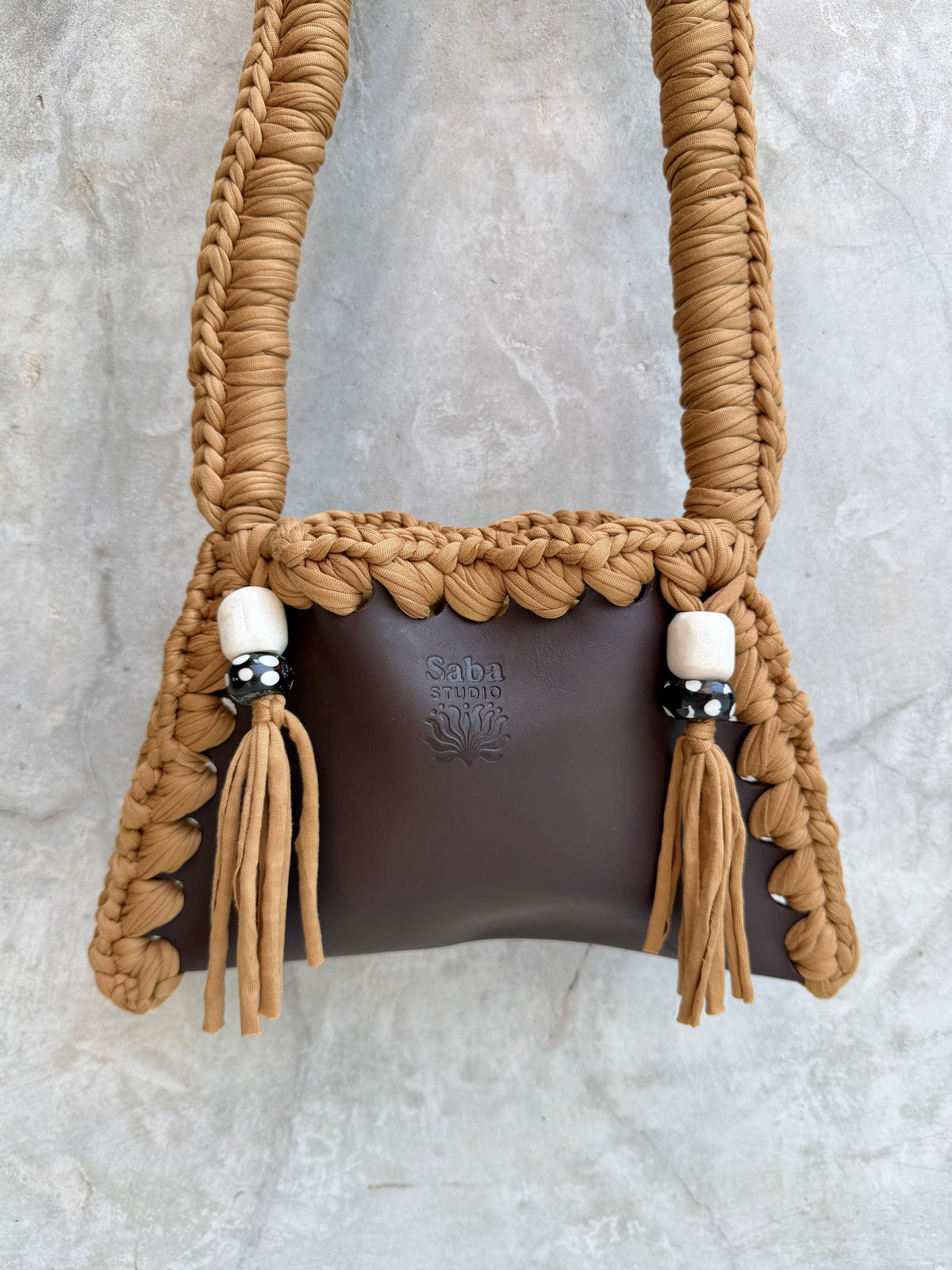 Close-up detail of Solara shoulder bag against a natural grey wall