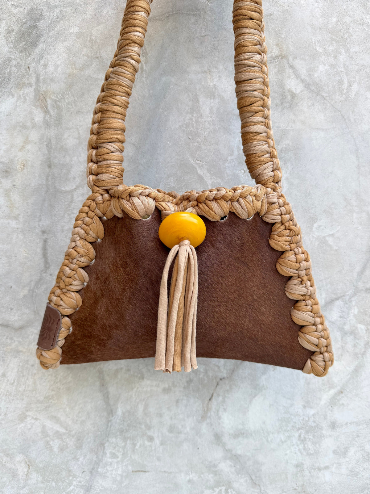 Close-up detail of Solara shoulder bag against a natural grey wall