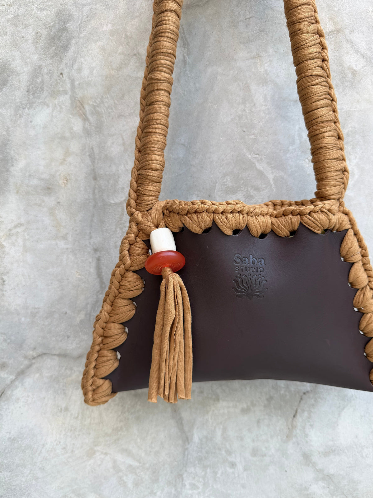 Close-up of the tan Solara shoulder bag with red and white bead detail